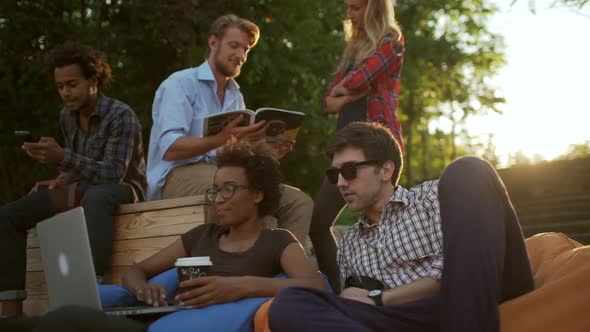 Five Interracial Male and Female Friends Sitting Standing in Park Talking Smiling Laughing with