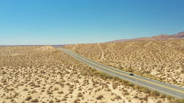 Descending aerial view of Midland Trail's Highway 14 through the Mojave Desert landscape