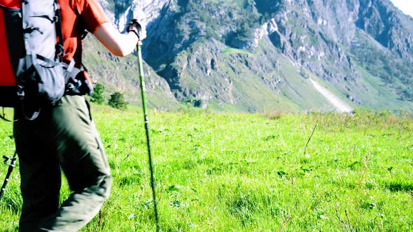 Hiking Man Walking on Green Mountain Meadow with Backpack. Summer Sport and Recreation Concept.
