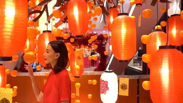 Beautiful Asian woman walking through a department store looking at orange Chinese lamps or lanterns