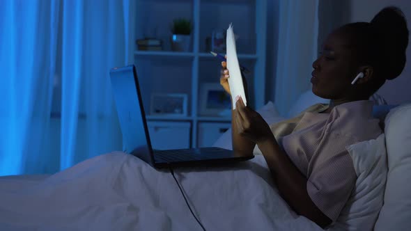 African Woman with Laptop Working in Bed at Night