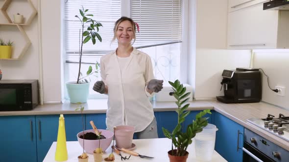 A Cute Girl Transplants a Plant at Home While Dancing Funny in Gardening Gloves