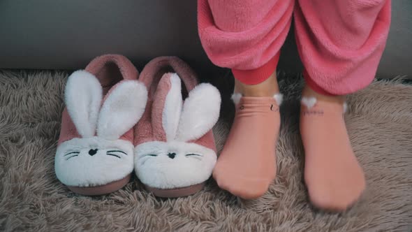 Young Woman Gets Out of Bed and Puts on Pink Slippers in the Morning