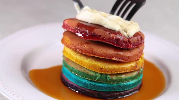 Eating rainbow pancakes with cream and syrup