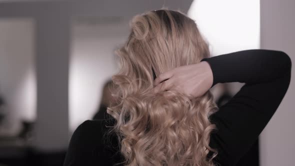 Blonde Straightens Her Hair with Her Hand Showing the Styling of the Wavy Curls