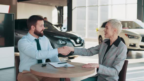 Charming Female Customer Reading Car Purchase Document and Shaking Hands While