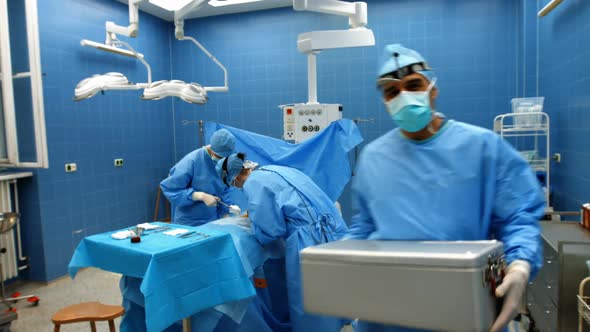 Portrait of surgeon holding ice box while colleagues performing operation