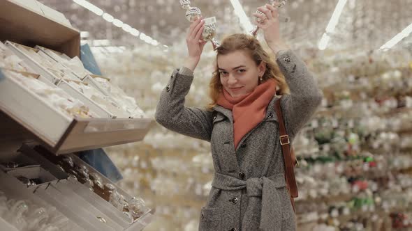 Funny Woman Buyer Trying on the Tops of the Christmas Tree in a Store