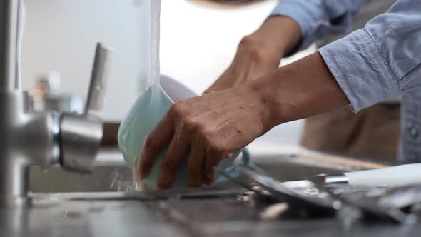 Close Up Footage of Dark Skinned Female's Hands Washing Blue Big Cup Under Water Jet in Slowmotion