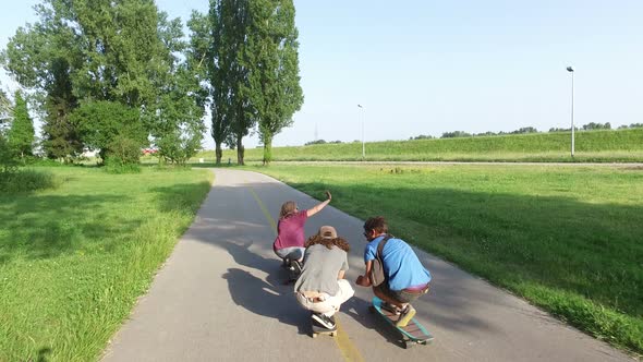 Back view of young friends riding on a skateboard in crouched position
