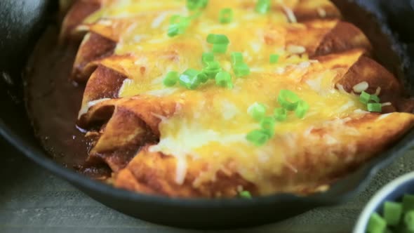 Homemade chicken enchiladas in cast iron frying pan.