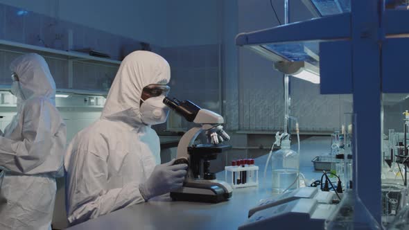 Male Scientist Using Microscope and Looking at Camera