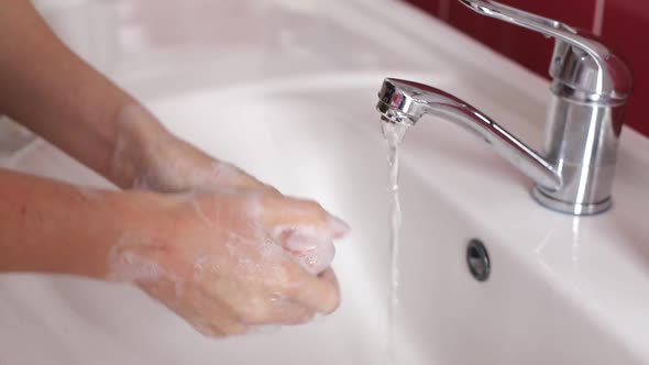 Woman Washes Her Hands in the Bathroom with Water Soap and Foam