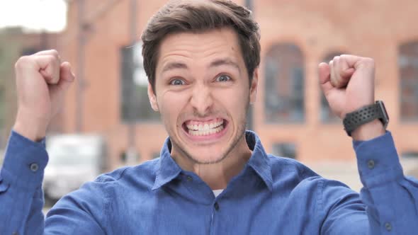 Young Man Celebrating Success Gesture in Office