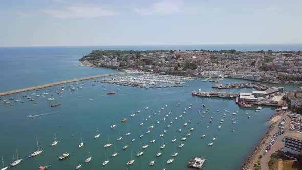 Flying over English harbour in Brixham. Boats docked in busy harbour.