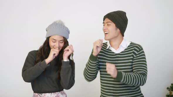 husband and wife smile dancing laughing around christmas tree at home living room