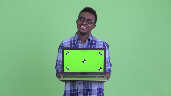 Happy Young African Hipster Man Thinking While Showing Laptop