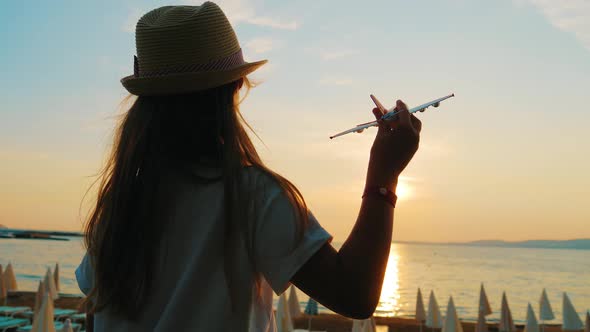 Silhouette Young Girl Plays with a Toy Airplane on Sunset