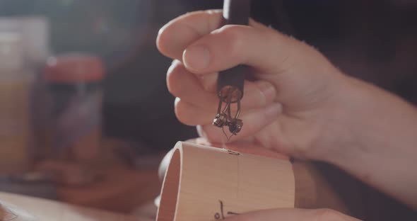 Woman making pyrography on wood, decorating a buddhist prayer wheel