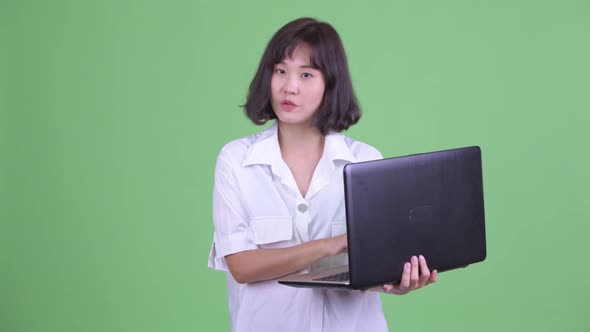 Happy Beautiful Asian Businesswoman Talking While Using Laptop