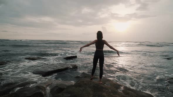 Silhouette of Girl on Ocean Beach Spreads Her Arms Wide Sunset on Background