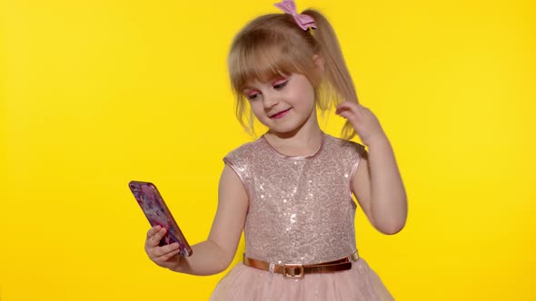 Child Girl Using Smartphone. Portrait of Blonde Kid Emotionally Makes Selfie on Mobile Phone