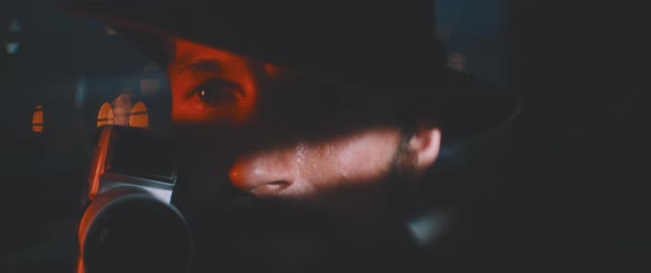 Close up of man through shutters and red lights using vintage camera