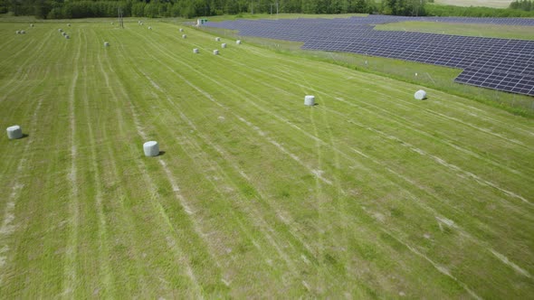 Solar panels next to a farm, hay, straw, field.