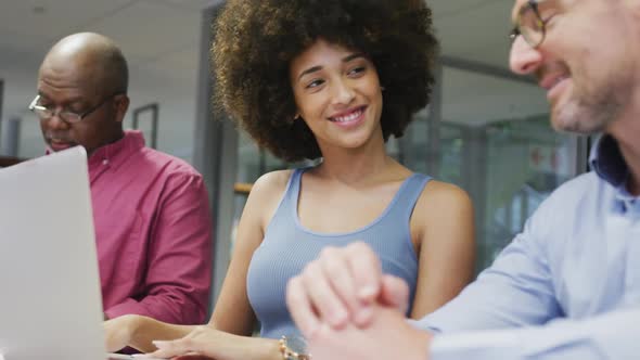 Diverse male and female business colleagues smiling and using laptop