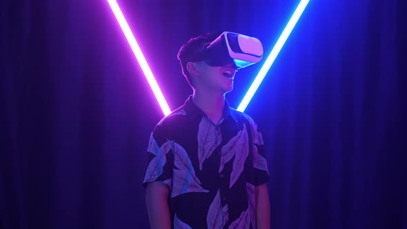 Futuristic, Entertainment Concept. Excited Asian Boy Using Virtual Reality Headset With Neon Light