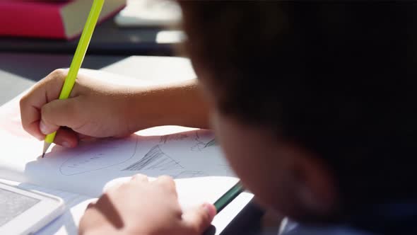 Attentive schoolboy doing their homework in classroom