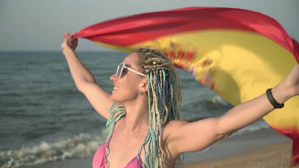 Young Attractive Woman with the Flag of Spain on the Sea Beach