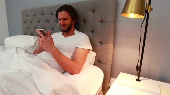 Young man using mobile phone in bed