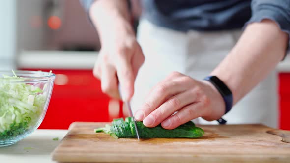 Male Hands with Knife Cuts Fresh Cucumber for Green Salad