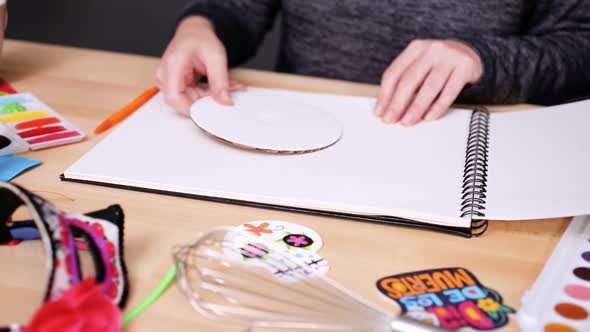 Step by step. Baker sketching a design of a cake for Dia de los Muertos holiday.