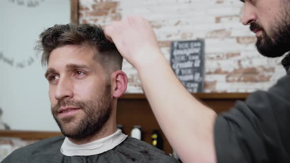 Man Barber Cutting Hair of Male Client with Clipper at Barber Shop