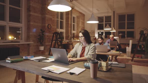 Woman Working on Laptop in Open Space Loft Office in Evening