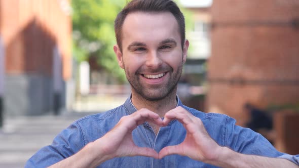 Portrait of Smiling Casual Man Gesturing Heart with Hand