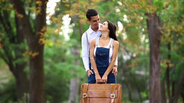 Teen couple with suitcase in the park in autumn time