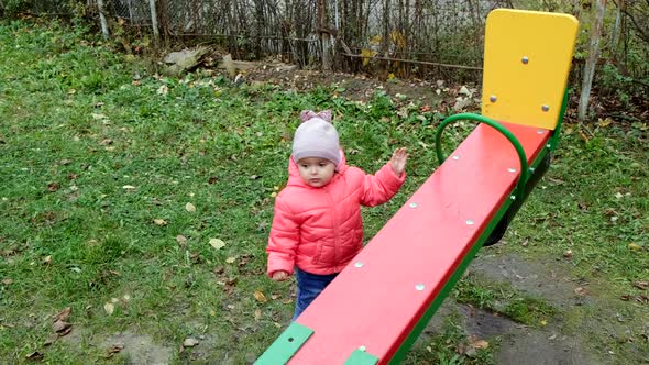 Cheerful toddler girl playing at children playground. Slow motion.