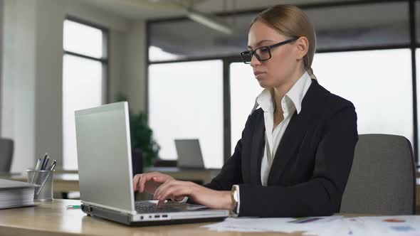 Female Worker Checking Time on Watch, Typing Quickly to Finish Report, Deadline