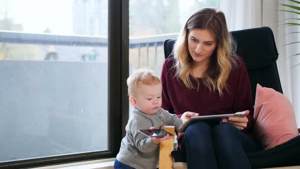 Mother using digital tablet while tacking care of her baby 4k