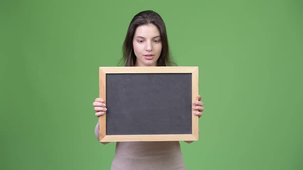 Young Beautiful Woman Looking Shocked While Holding Blackboard