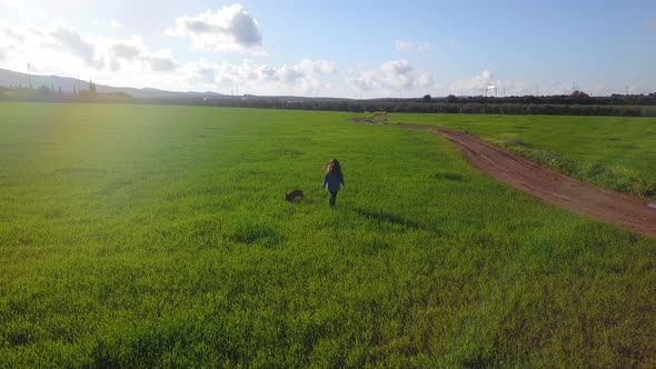 A Young Girl with dog Walking Along A Wheat Field