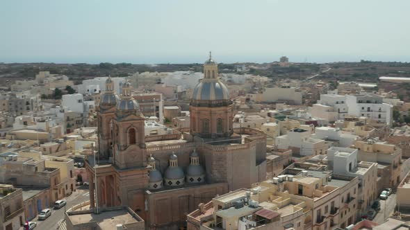 Beautiful Blue and Brown Church Towers in Small Mediterranean Town on Malta Island, Aerial Slide