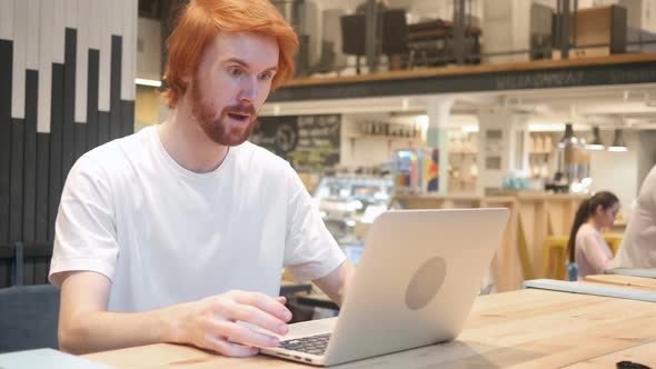 Excited Redhead Beard Man Celebrating Success Sitting in Cafe