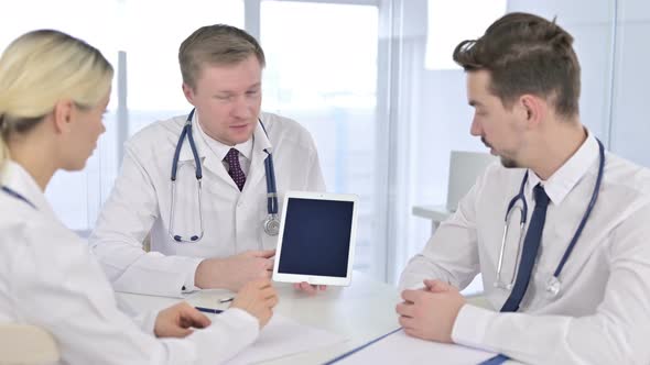 Professional Male Doctor Having Discussion with Team on Tablet