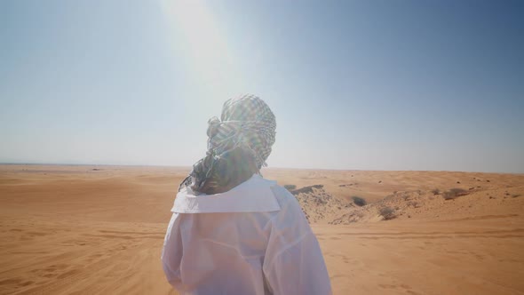 Back View of Young Woman with Covered Head Looking at the Desert