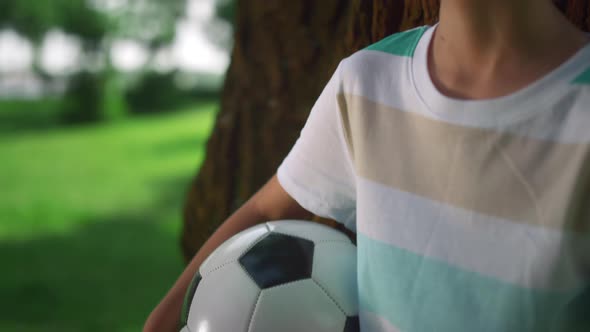 Portrait of Boy Holding Ball Near Tree