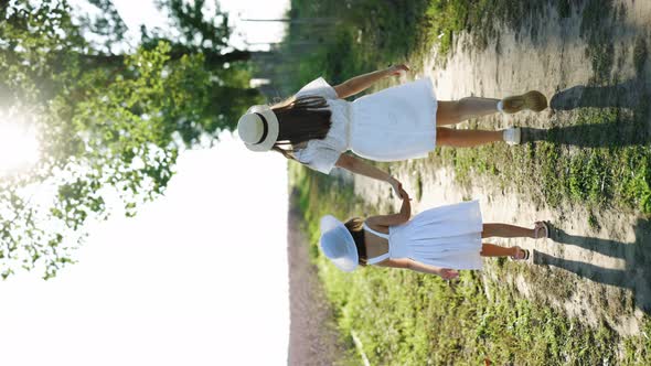 Vertical Video of Happy Family Mother and Little Kid Holding Hands Walks in the Park at Sunset